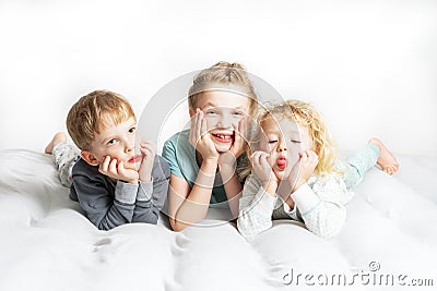 Friendship: three children lie on the bed and make funny faces Stock Photo