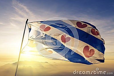 Friesland Province of Netherlands flag textile cloth fabric waving on the top sunrise mist fog Stock Photo