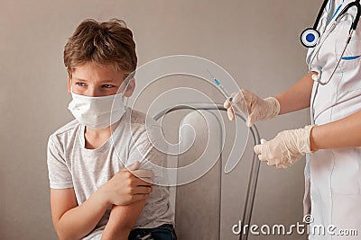 schoolboy medical mask crying, afraid injection, doctor standing rubber gloves, holding syringe. concept health care Stock Photo