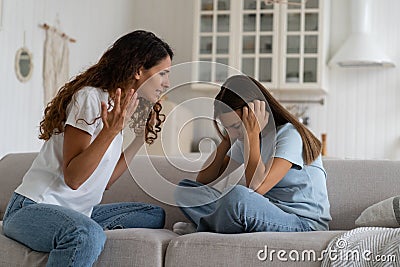 Frightened teenage girl covering ears listening to mother cries chastising child sits on sofa Stock Photo