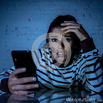 Worried unhappy young woman suffering from cyberbullying and harassment online by mobile phone Stock Photo