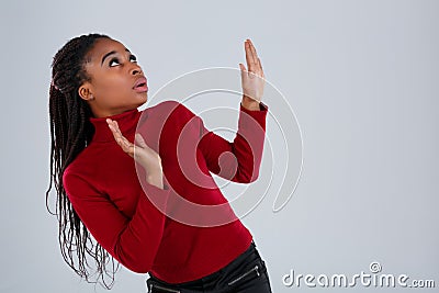 A girl, Afro-American looks a little bent and looks up with a frightened look and raised her hands in front of her. Stock Photo