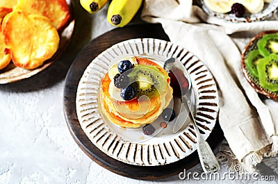 Fritters with honey, banana, blueberries and kiwi on a gray background Stock Photo