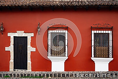 front door and windows with safety bars in a red painted small, old house in Guatemala Stock Photo