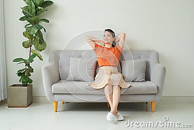 Front full length view tranquil millennial pretty woman relaxing on comfortable sofa in living room Stock Photo