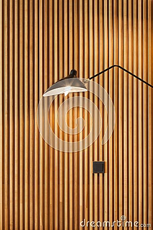 Front of modern wooden separator modern wall-mounted lamp on textured wood wall. Stock Photo