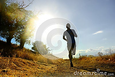 Front silhouette young sport man running cross country workout at summer sunset Stock Photo