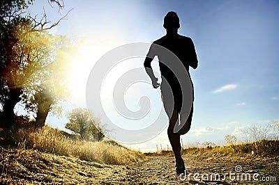 Front silhouette young sport man running cross country workout at summer sunset Stock Photo