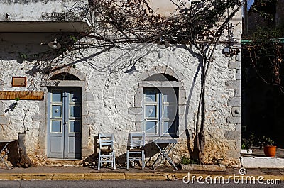 Front of small picturesque store or resturant with table and chairs on sidewalk closed for holiday on main street of small Greek t Stock Photo