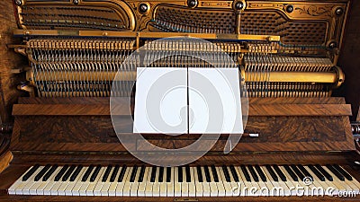 Front view of an antique piano with the keyboard open and two sheets of blank paper on support for musical notes Stock Photo