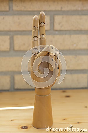 Articulated wooden hand with two raised fingers Stock Photo