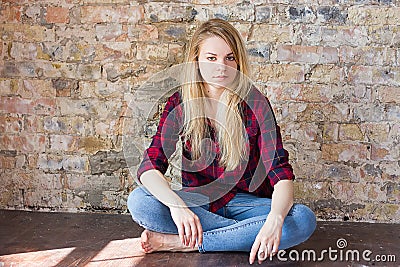 Front view of attractive white girl sitting on wooden floor Stock Photo