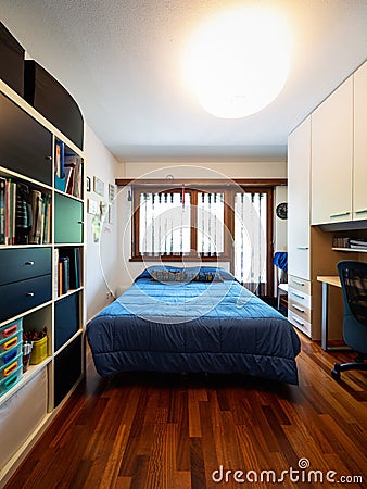 Front view bedroom with blue blankets, bookshelf and parquet Stock Photo