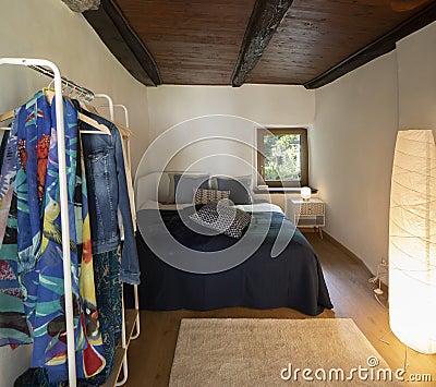 Front view bedroom with double bed, bedside table with a lamp above and a wardrobe on the left Stock Photo