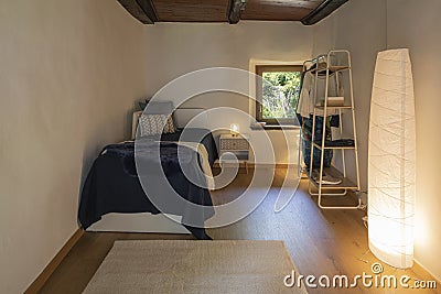 Front view bedroom with single bed, bedside table with a lamp above and a wardrobe on the left Stock Photo