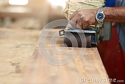 Front view of belt sander working on a piece wood with hands of worker with copy space. Selective focus and shallow depth of field Stock Photo