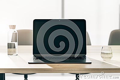 Front view on blank black modern laptop screen with space for your logo or text on wooden table with glass and bottle of water on Editorial Stock Photo