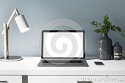 Front view on blank white laptop display on white table with stylish vase, lamp and smartphone. Mock up Editorial Stock Photo