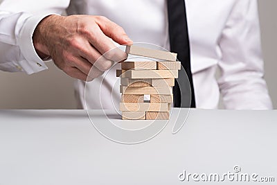 Front view of businessman building a tower of wooden pegs Stock Photo