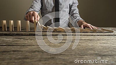 Front view of a businessman stopping domino effect with his finger Stock Photo