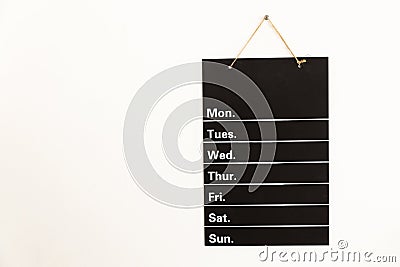 Front view of empty weekly to do list white grid timetable schedule on black chalkboard hanging on wall Stock Photo