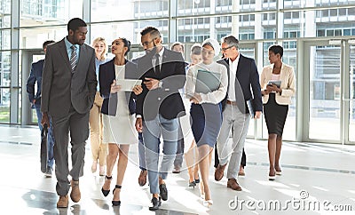 Front view of group of diverse business people walking together in lobby office Stock Photo