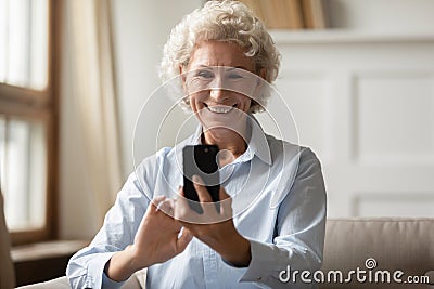 Happy 70s grandmother taking selfie on smartphone. Stock Photo