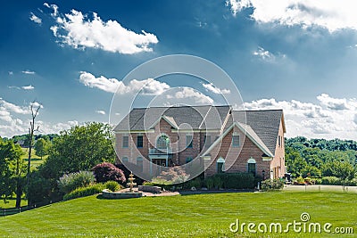 Front view of a large brick country house. Large freshly cut lawn and trees in the foreground Editorial Stock Photo