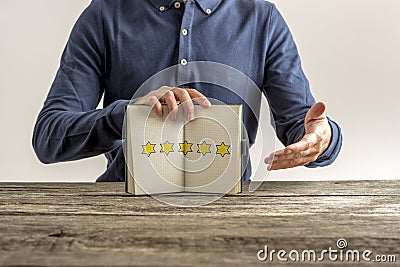 Front view of a man presenting an open notepad with five golden Stock Photo