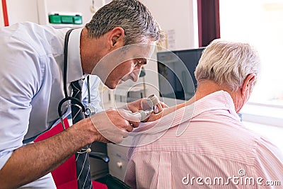 Male dermatologist examining senior patient with dermatoscopy Stock Photo