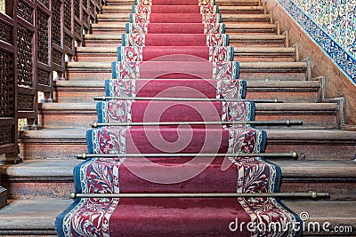 Front view of old ascending wooden stairs with ornate red carpet Stock Photo