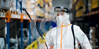 Man worker with protective mask and suit disinfecting industrial factory with spray gun. Stock Photo