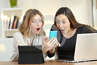 Amazed friends using multiple devices at home Stock Photo