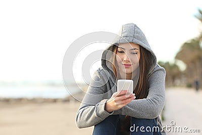 Front view of a relaxed teen uses a smart phone on the beach Stock Photo