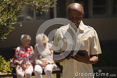 Front view of senior man suing digital tablet in garden Stock Photo