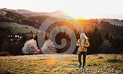 Front view of senior woman hiker walking outdoors in nature at sunset. Stock Photo