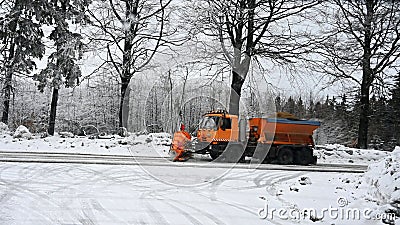 View of snowplow service truck - gritter car spreading salt on the road. Maintenance of roads in winter in the mountains Stock Photo