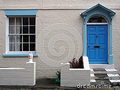 front view of a typical old small english terraced brick house white painted wall and blue door Stock Photo