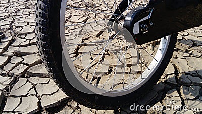 The front wheel of a school bike against a background of dried up cracked clay soil. Racing in the desert. Close-up bicycle rubber Stock Photo