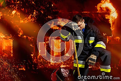 The firefighter is powerless in extinguishing aggressive flame, being all in ash. Stock Photo