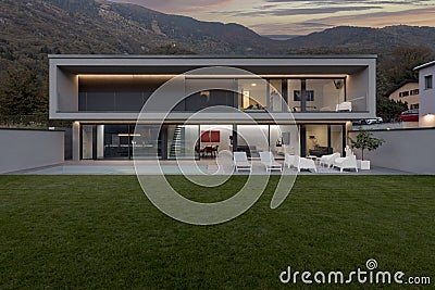 Frontal view modern house with swimming pool and garden illuminated by LED lights at sunset Editorial Stock Photo