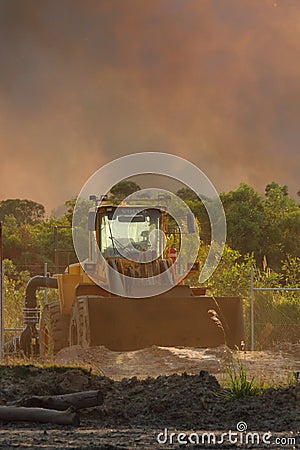 Frontend loader with backdrop of approaching bushfire Editorial Stock Photo