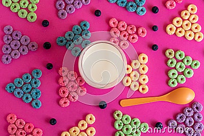 Froot loops in the shape of a triangle blue, green, purple, pink, orange on a pink cardboard Stock Photo