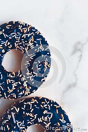 Frosted sprinkled donuts, sweet pastry dessert on marble table background, doughnuts as tasty snack, top view food brand flat lay Stock Photo