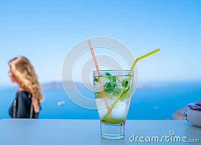 Frosty glass with mojito drink in focus in foreground with person in background out of focus Stock Photo