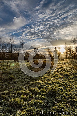 Frosty morning sunrise with short building on the left and a grassy field in the foreground on the Sammamish River trail in Stock Photo