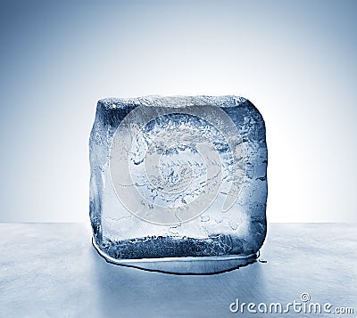 Cold blue ice block melting into water puddle on metal surface Stock Photo