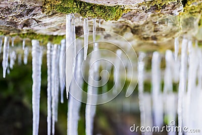Frosty white icicles hanging from a rocky overhang micro-cave en Stock Photo