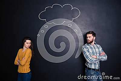 Frowning angry couple thinking identically over background of chalkboard Stock Photo