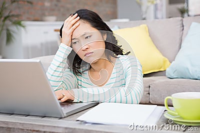 Frowning brunette using laptop Stock Photo